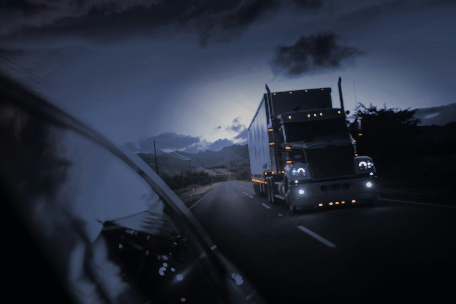 A semi-truck with its marker lights on, driving on a highway at night